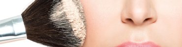 Makeup brush sweeping powder across a woman's cheek
